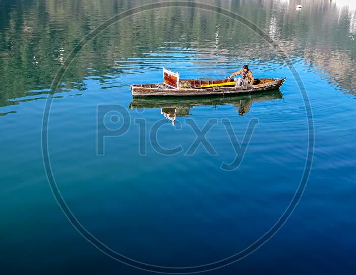 Boatman Rowing His Small Boat In Blue Waters Of Bhimtal Lake.