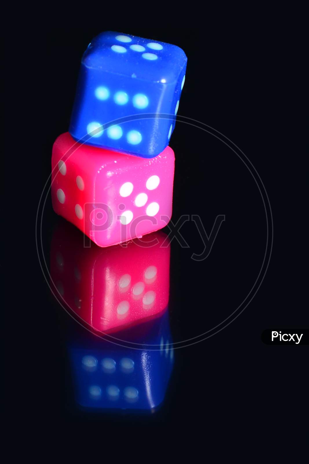 Multi Color Dice Placed On Top Of Each Other Over Reflecting Surface.
