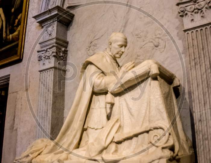 Seville, Spain- June 18, 2017: Marble Sculpture Of A Saint Kneeling And Praying Inside The  Gothic Cathedral In Seville, Spain June 2017