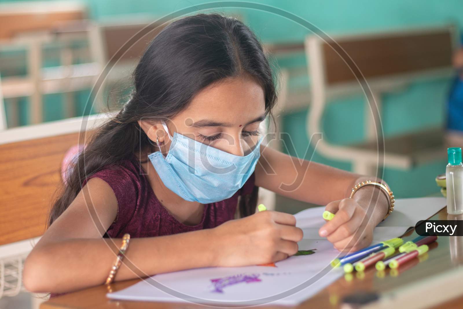Young Girl Kid In Medical Mask Busy In Drawing Sketch At Classroom - Concept Of Safety Masures At School Due To Coronavirus Or Covid-19 Pandemic.