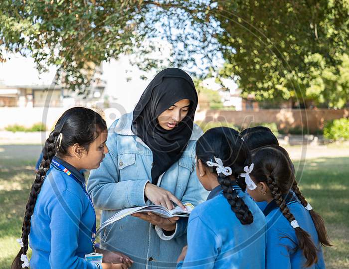 Jodhpur, Rajasthan, India - Jan 10Th 2020: Muslim Teacher Surrounded By Students Helping To Solve Their Problem After School Over While Pointing In The Notebook, Education Concept