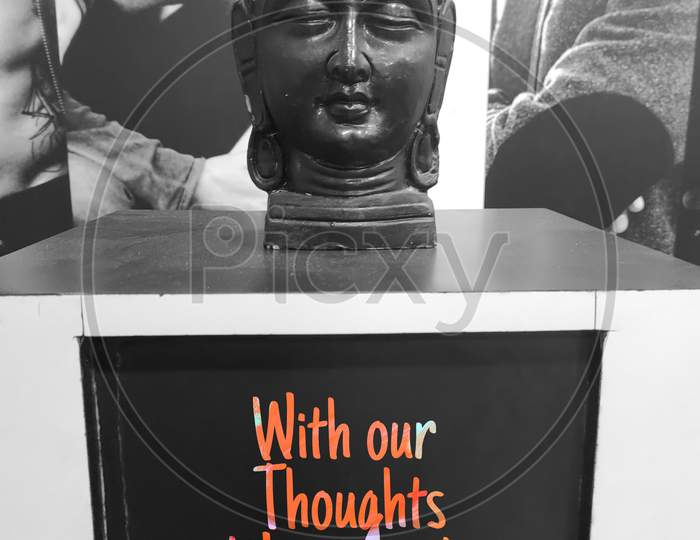 Black coloured home decor piece of Buddha, With the quote "with our Thoughts we make the world". coloured Text