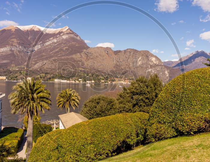 Italy, Bellagio, Lake Como, A Garden With A Mountain In The Background