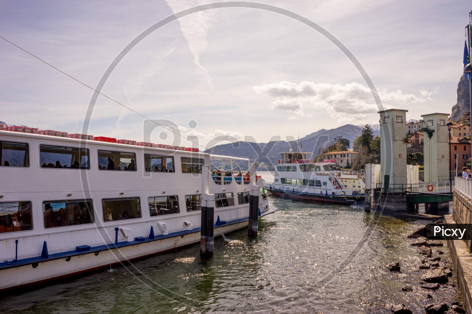 Menaggio, Italy-April 2, 2018: Traffic Jam With Ferry Boat On The Lake Como Transporting People With Mountain In Background