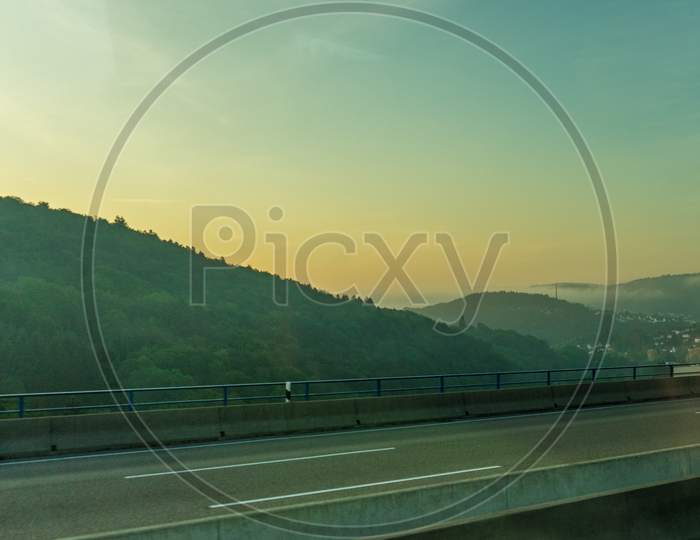 Germany, Frankfurt, Sunrise, A Highway With A Mountain In The Background