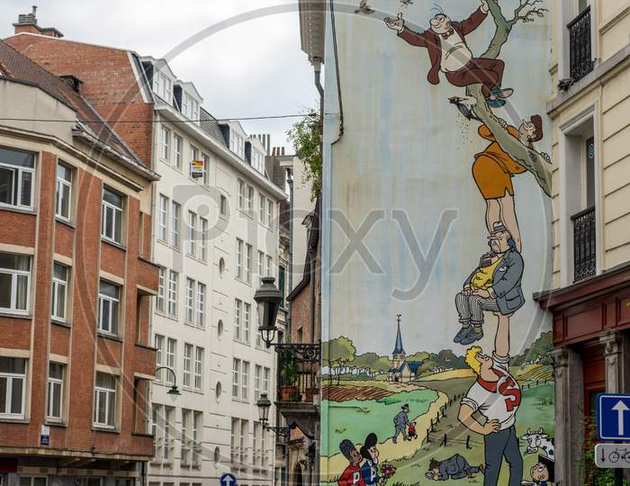Brussels, Belgium - April 17 :  A Man Walks Past Of A Fresco Of People Sitting On Trees Painted On The Walls Of A Building At Brussels, Belgium, Europe On April 17.