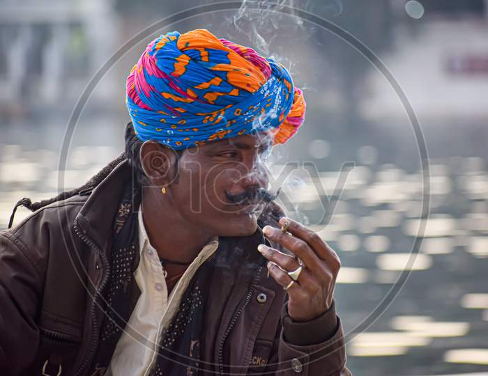 A rajasthan man with colourful turban and cigarette in his hand.
