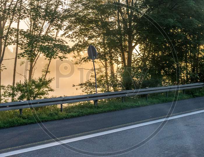 Germany, Frankfurt, Sunrise, An Empty Road With Trees On The Side Of The Street