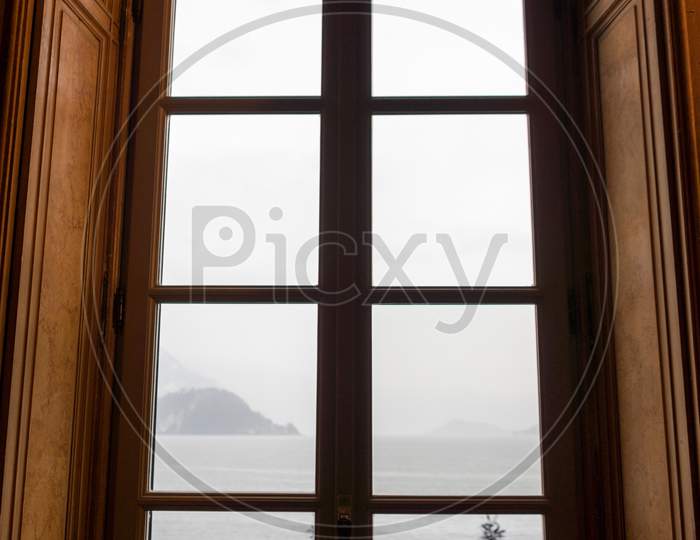 Italy, Varenna, Lake Como, A View Of A Large Window Overlooking A Lake