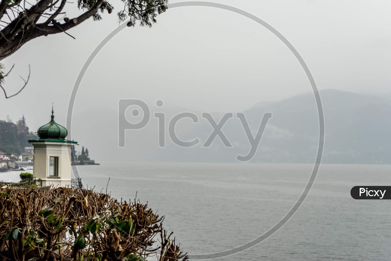 Italy, Varenna, Lake Como, A Large Body Of Water Surrounded By Trees