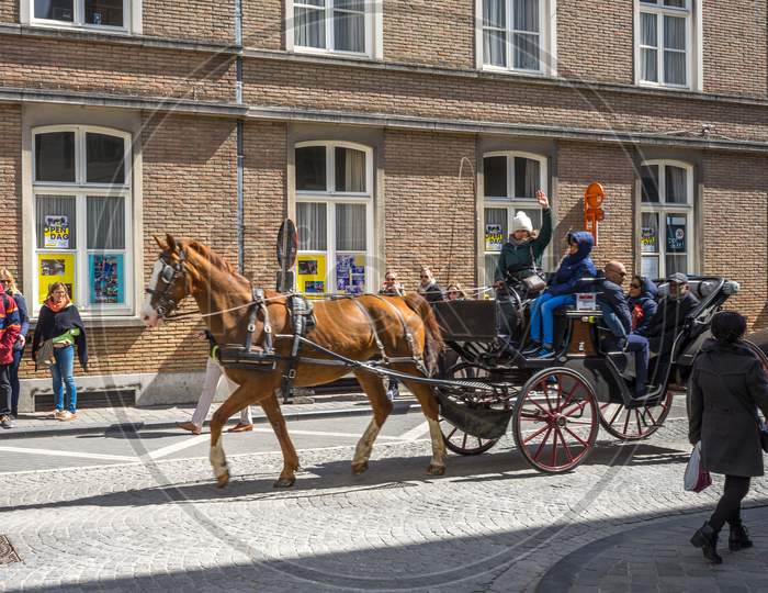 Brugge, Belgium - April 17 :  Toursists Travelling In A Horse Drawn Carriage At Bruges, Belgium