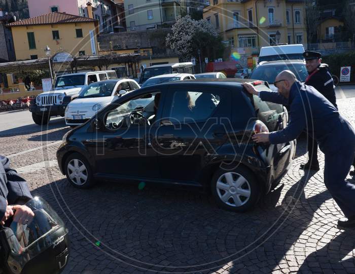 Menaggio, Italy-April 2, 2018: People Pushing A Broken Down Toyota Car, Lombardy
