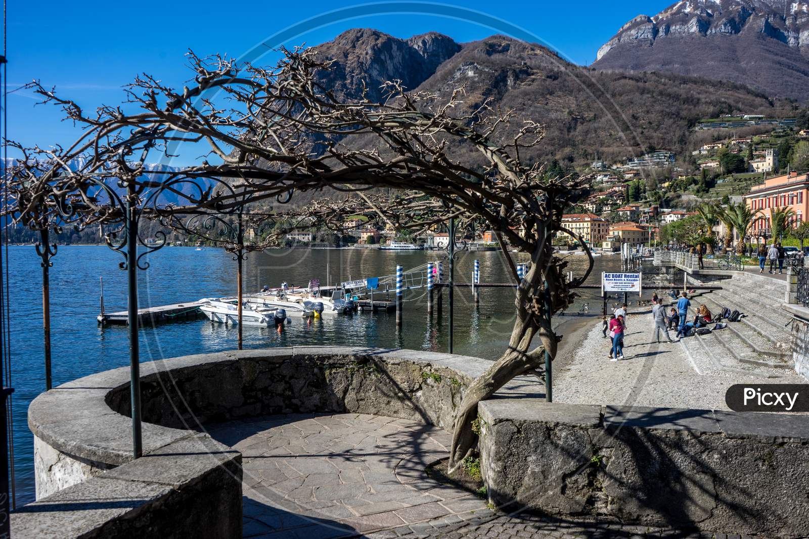 Menaggio, Italy-April 2, 2018: People Relaxing At The Waterside Quay, Menaggio, Lombardy