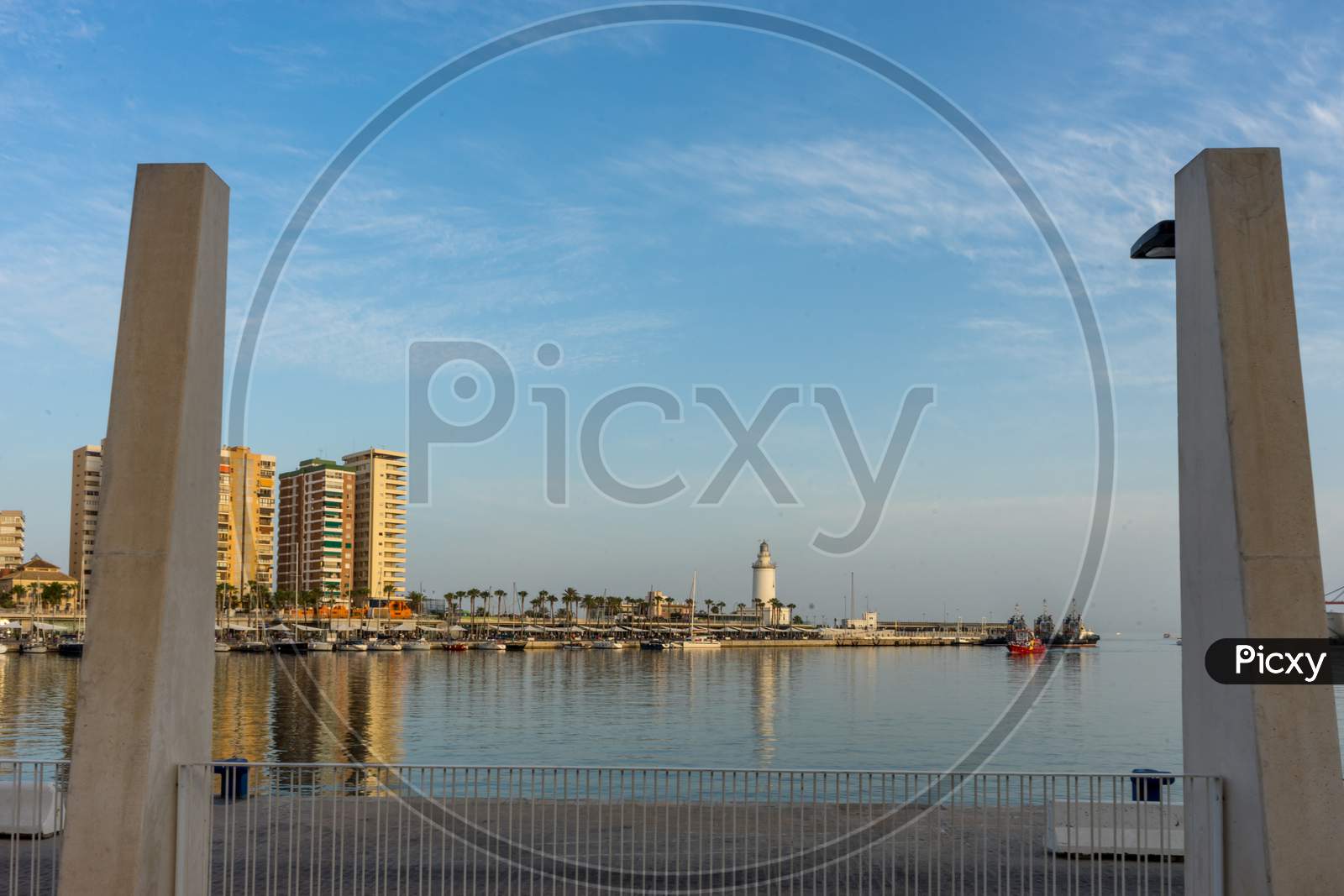 White Lighthouse And The Tall Buildings Of Malaga With Their Reflections In Malaga, Spain, Europe