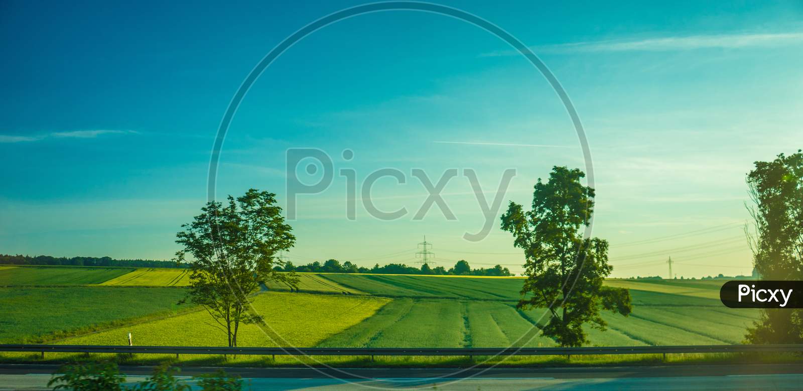 Germany, Frankfurt, Sunrise, A Large Green Field With Trees In The Background