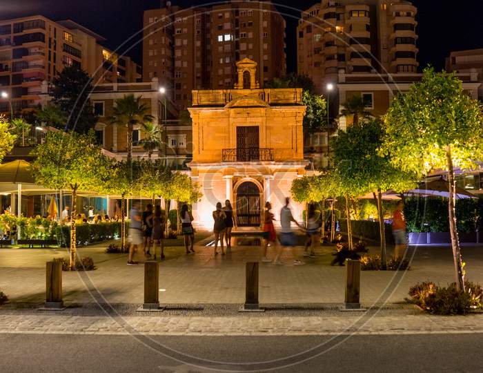 Spain, Malaga,  Málaga People Standing On Illuminated Street Against Buildings In City At Night