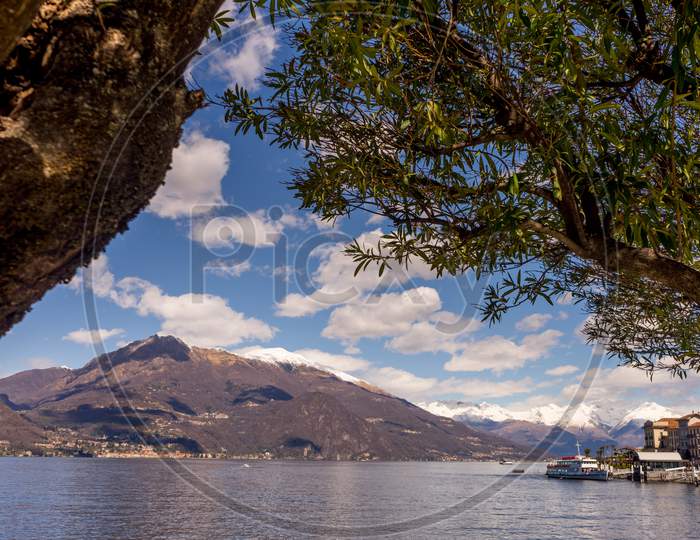 Italy, Bellagio, Lake Como, A Large Body Of Water With A Mountain In The Background