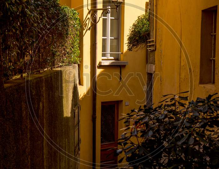 Italy, Menaggio, Lake Como, A Yellow Wall In The Middle Of A Sidewalk
