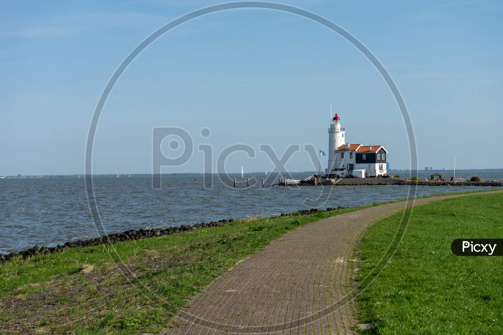 Netherlands,Wetlands,Maarken, Lighthouse Amidst Sea And Buildings Against Sky