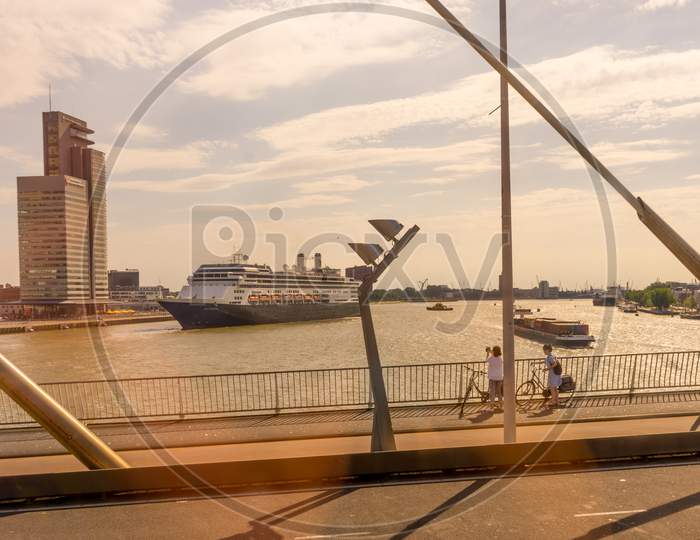 Rotterdam, Netherlands - 27 May: Cyclist On Erasmus Bridge At Rotterdam With Cruise Ship In Background On 27 May 2017. Rotterdam Is A Major Port City In The Dutch Province Of South Holland