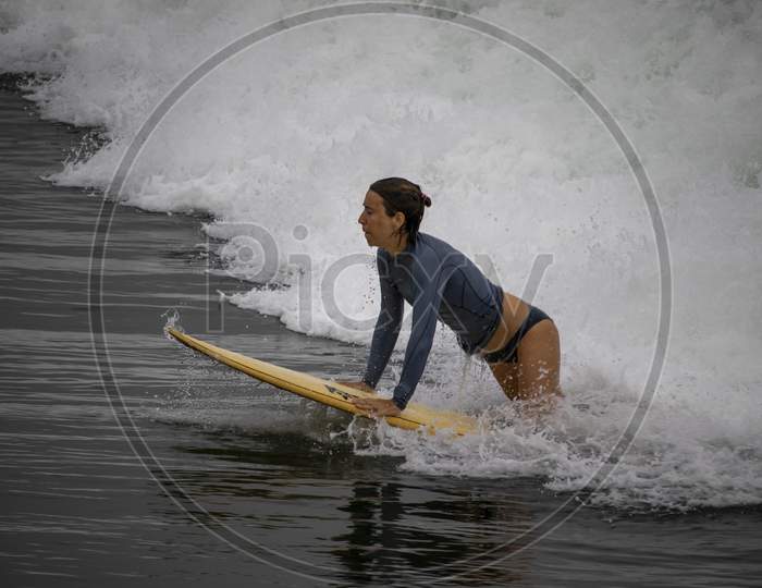 A Beautiful Young Foreign Lady Surfing From The Surfboard Amid The Waves Of Seawater