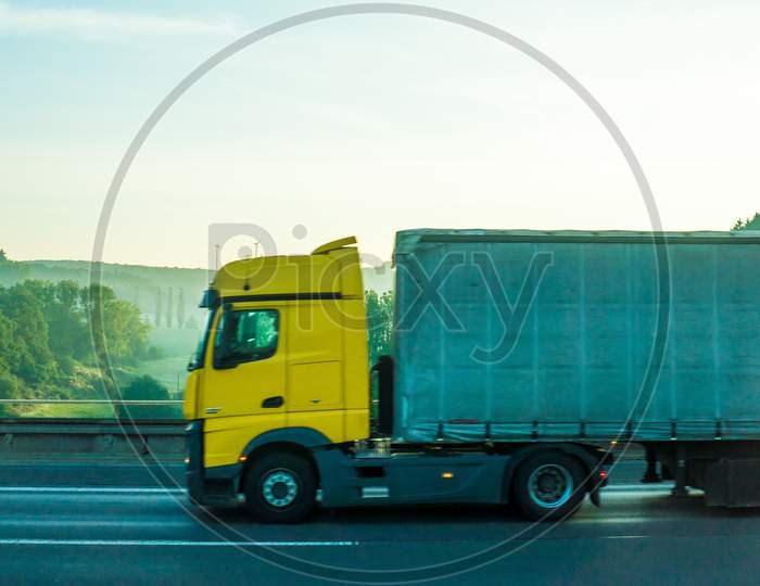 Germany, Frankfurt, Sunrise, A Large Blue Truck Is Parked On The Side Of A Road