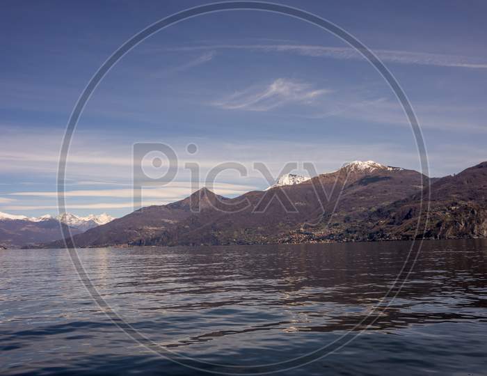 Italy, Menaggio, Lake Como, A Large Body Of Water With A Mountain In The Background