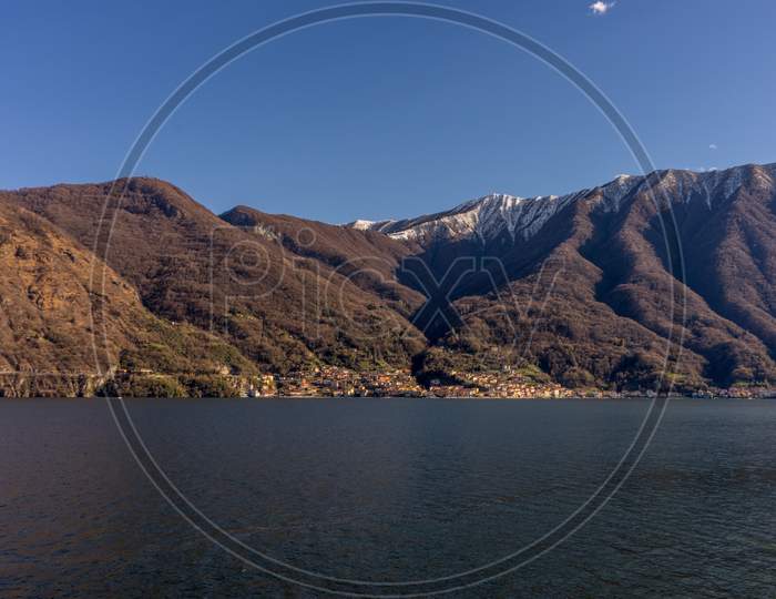 Italy, Lecco, Lake Como, A Large Body Of Water With A Mountain In The Background