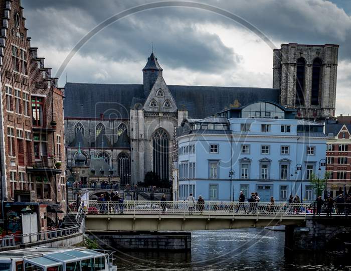 Ghent Belgium - April 15 : Toursists Walk Across The Bridge Near The Saint Michael'S Church In Ghent, Belgium