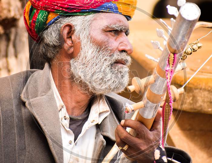 A portrait of old Rajasthan man playing a musical instrument