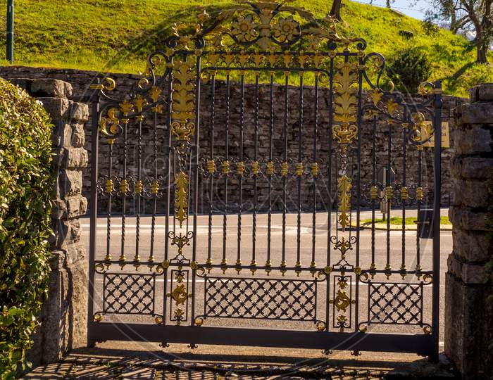 Italy, Bellagio, Lake Como, A Bench Next To A Bellagio, Italy-April 1, 2018: The Mansion Gate At I Giardini Di Villa Melzi