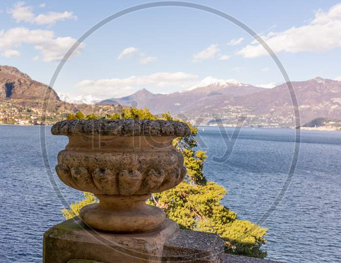 Italy, Lecco, Lake Como, A Body Of Water With A Mountain In The Background