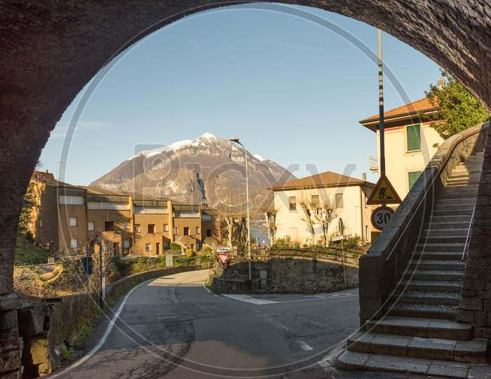 Italy, Bellagio, Lake Como, Snow Capped Alps Under Arch With Staircase Winding Road