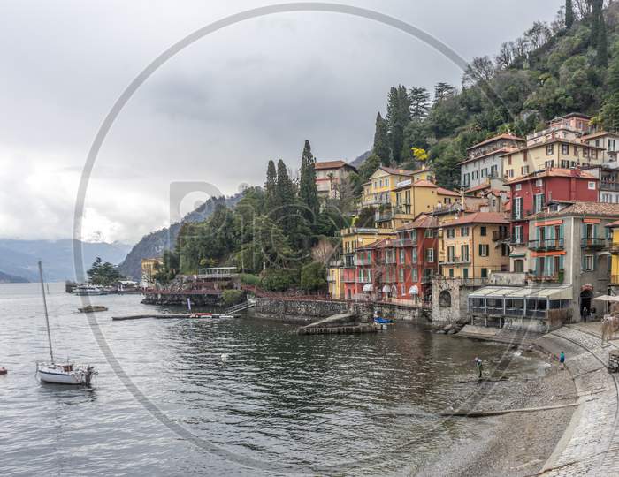 Italy, Varenna, Lake Como, Lake Como, A Small Boat In A Body Of Water With Buildings In The Background With Lake Como In The Background