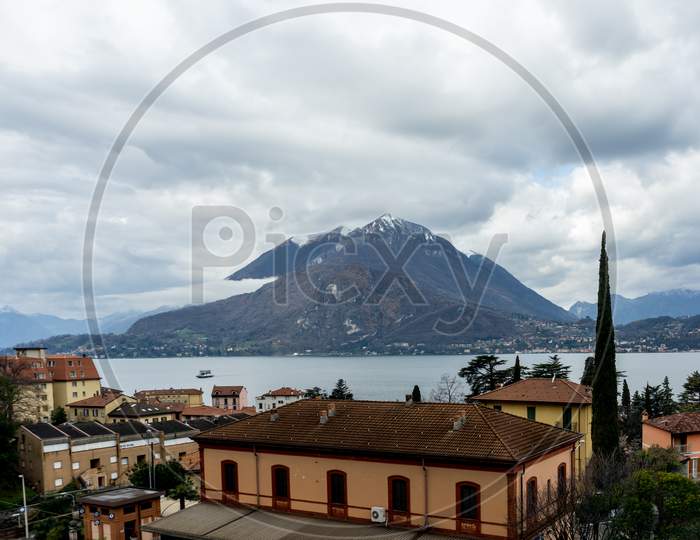 Italy, Varenna, Lake Como, A Large Lake With A Mountain In The Background