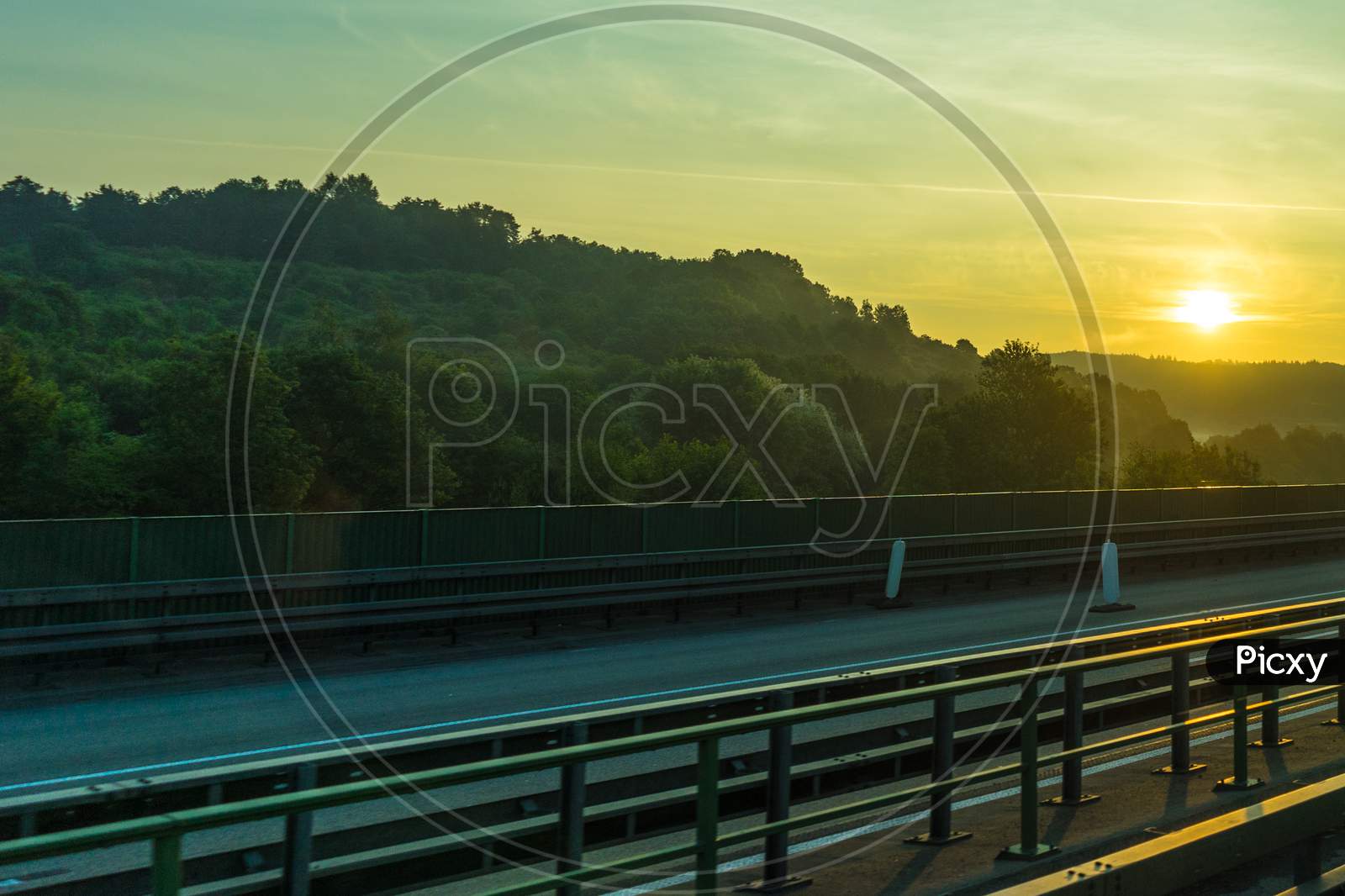 Germany, Frankfurt, Sunrise,, A Large Long Train On A Track Next To A Body Of Water