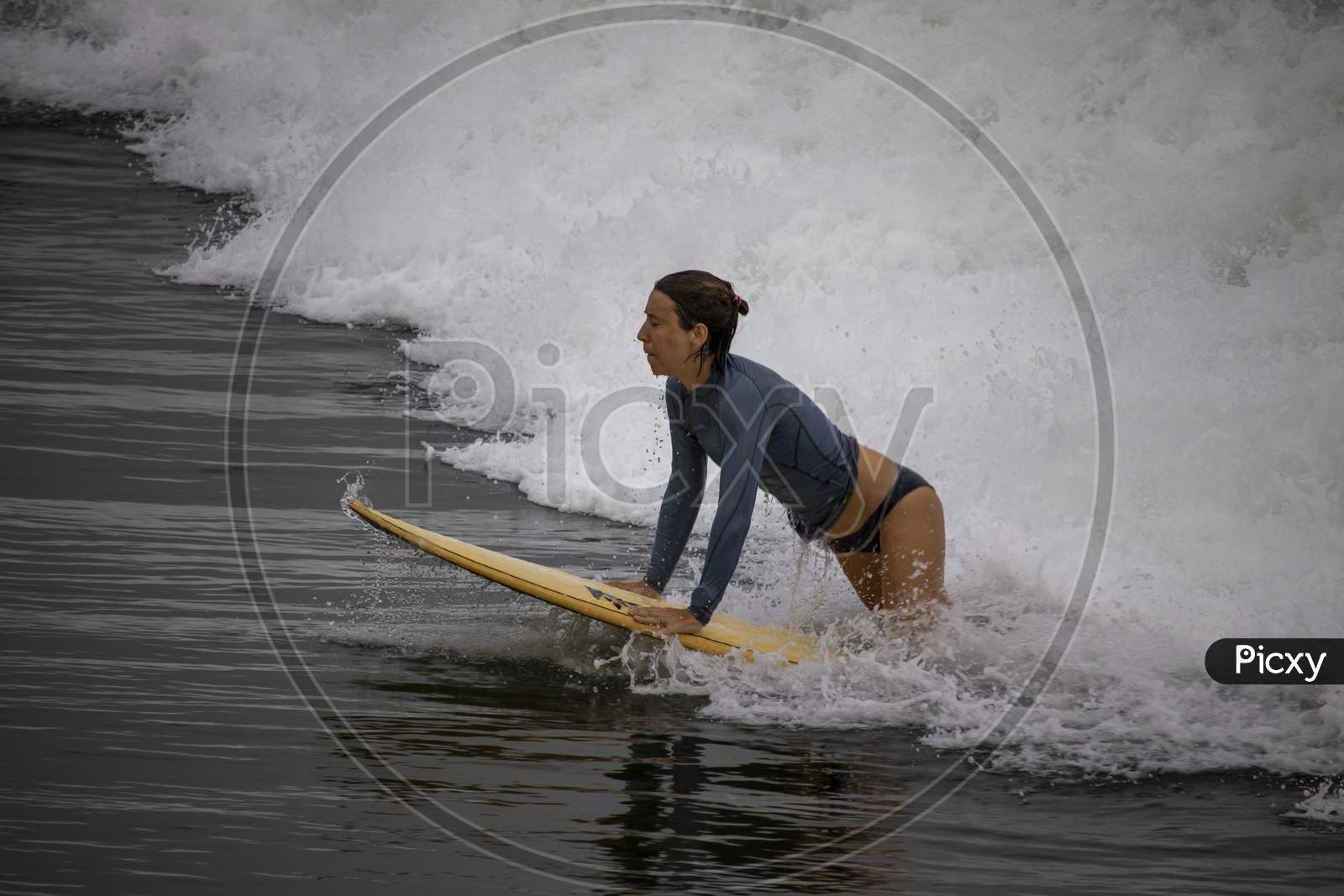 A Beautiful Young Foreign Lady Surfing From The Surfboard Amid The Waves Of Seawater