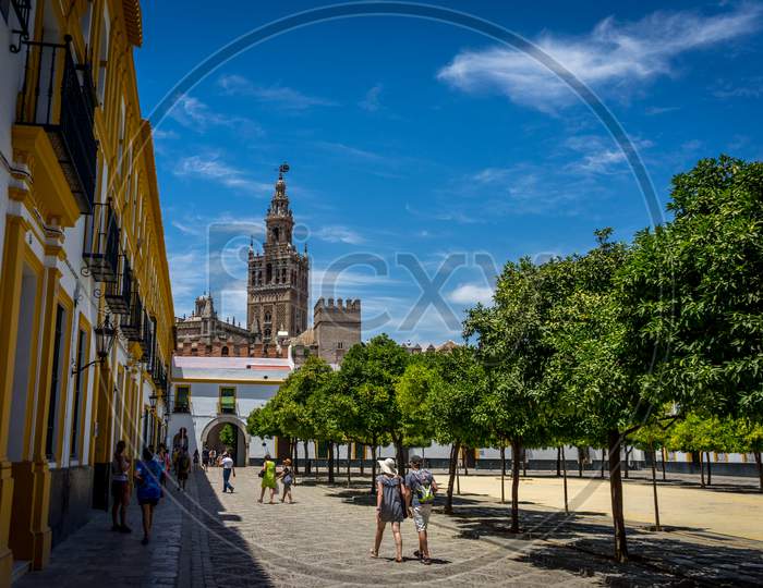 The Giralda Bell Tower With People In The Foreground In Seville, Spain, Europe
