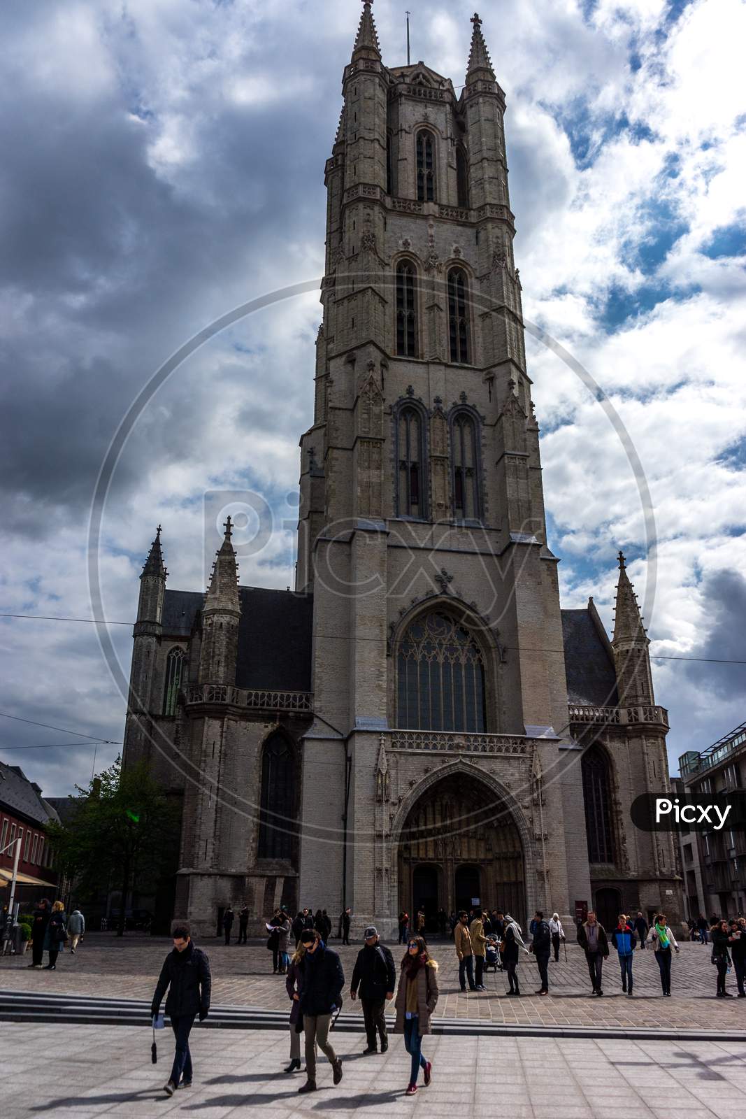 Ghent,Belgium - April 17 :  Tourists Walk In Front Of The 91-Metre-Tall Belfry Of Ghent, Belgium, Europe On A Bright Summer Day With Blue Sky At Ghent, Belgium, Europe