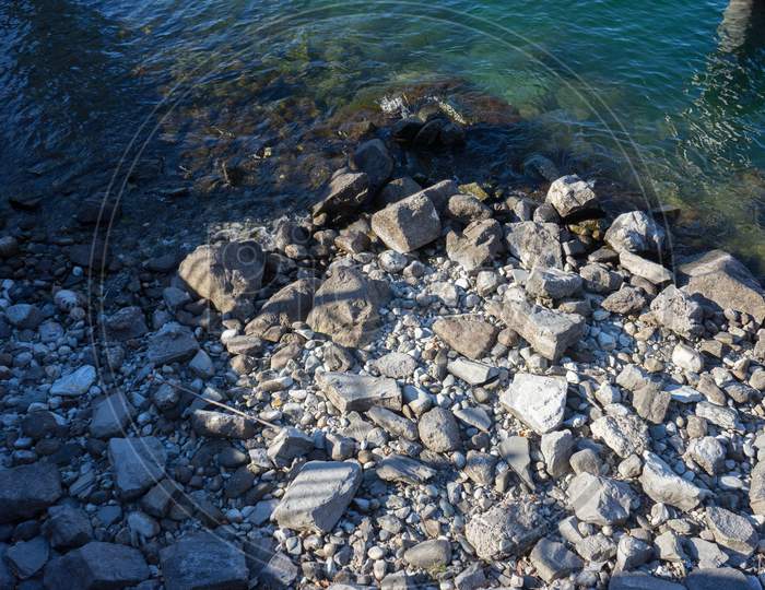 Italy, Menaggio, Lake Como, A Close Up Of A Rock Next To Water