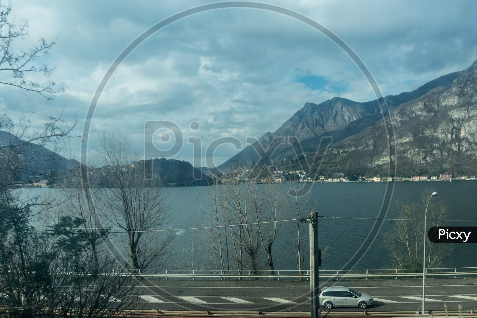 Italy, Varenna, Lake Como, A View Of A Body Of Water With A Mountain In The Background