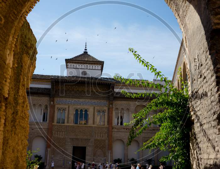 Seville, Spain - June 19: The Real Alcazar, Seville, Spain On June 19, 2017. Tourists Walking In The Courtyard On A Warm Summer Day.