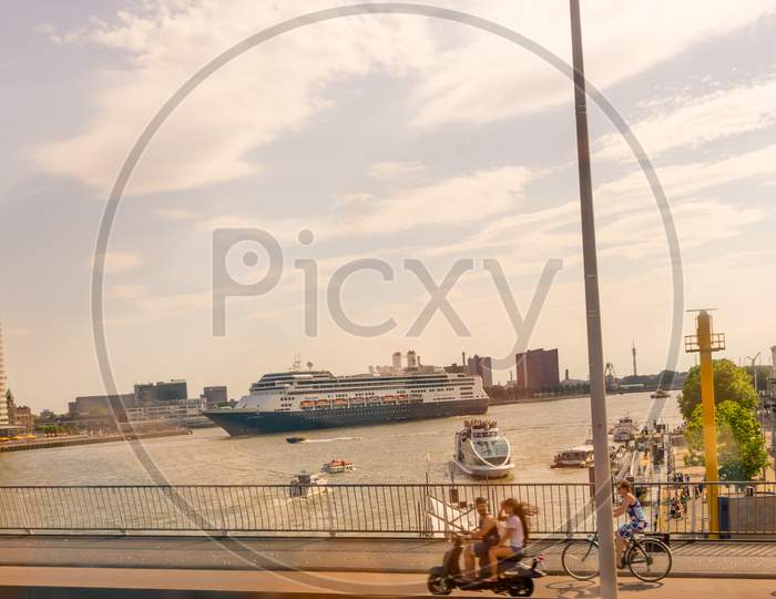 Rotterdam, Netherlands - 27 May: Cyclist On Erasmus Bridge At Rotterdam With Cruise Ship In Background On 27 May 2017. Rotterdam Is A Major Port City In The Dutch Province Of South Holland