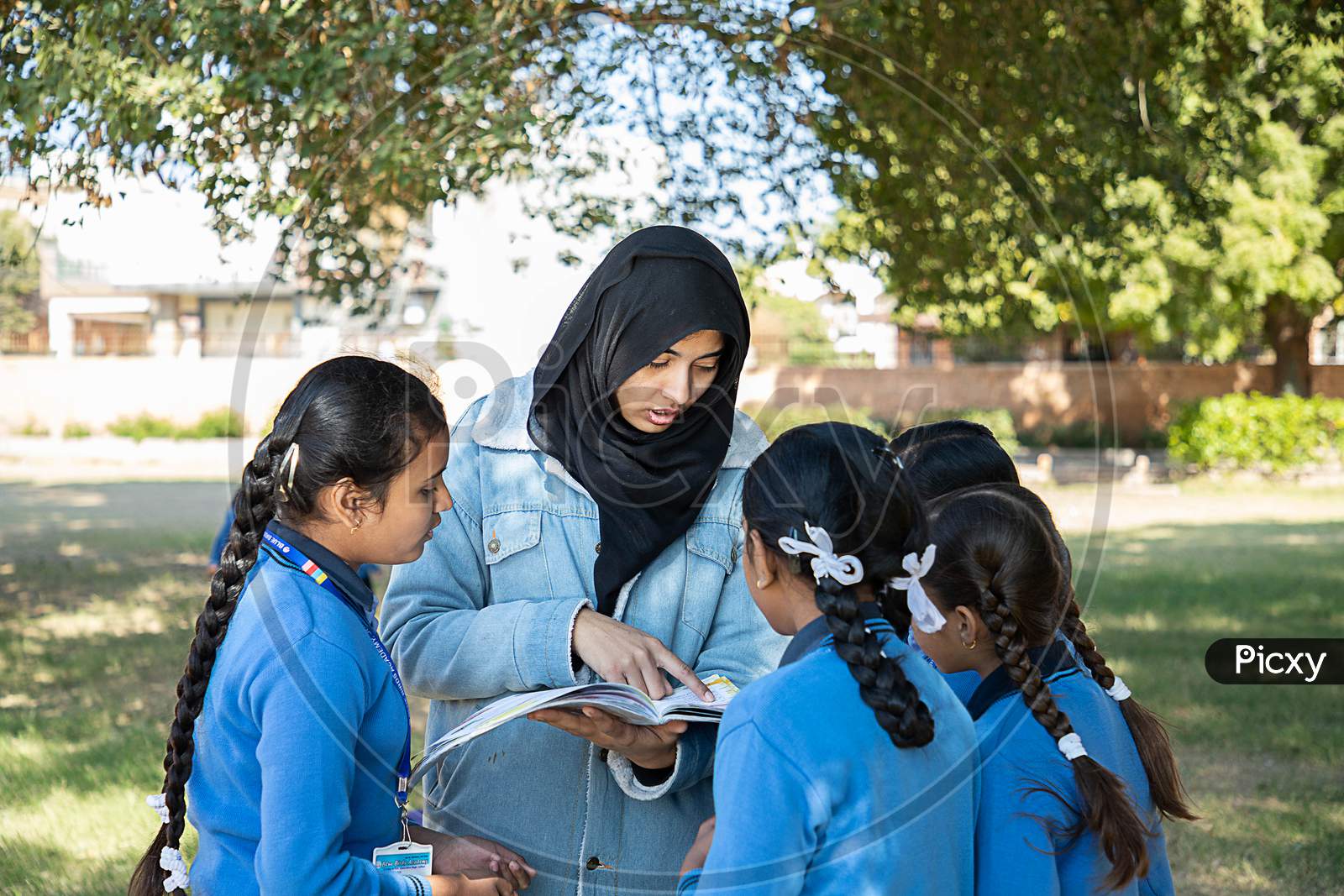 Jodhpur, Rajasthan, India - Jan 10Th 2020: Muslim Teacher Surrounded By Students Helping To Solve Their Problem After School Over While Pointing In The Notebook, Education Concept