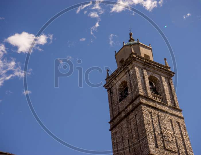 Italy, Bellagio, Lake Como, A Large Tall Tower With A Clock On The Side Of A Building