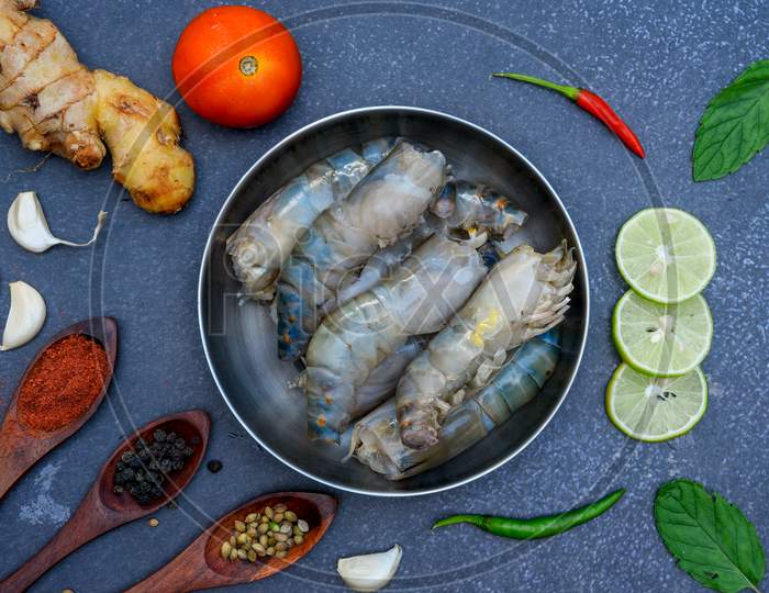 raw shrimps on wooden cutting board plate / fresh shrimp prawns for cooking with spices lemon on dark background in the seafood restaurant