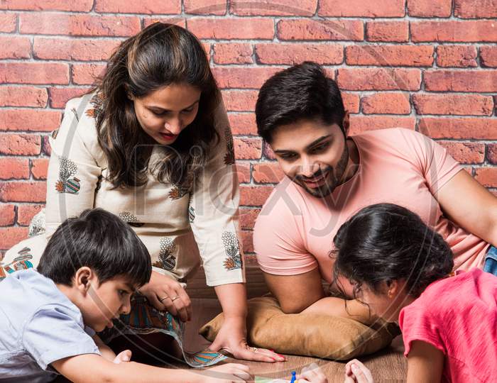 Indian Happy Family Playing Board Games Like Chess, Ludo Or Snack And Ladder At Home In Quarantine