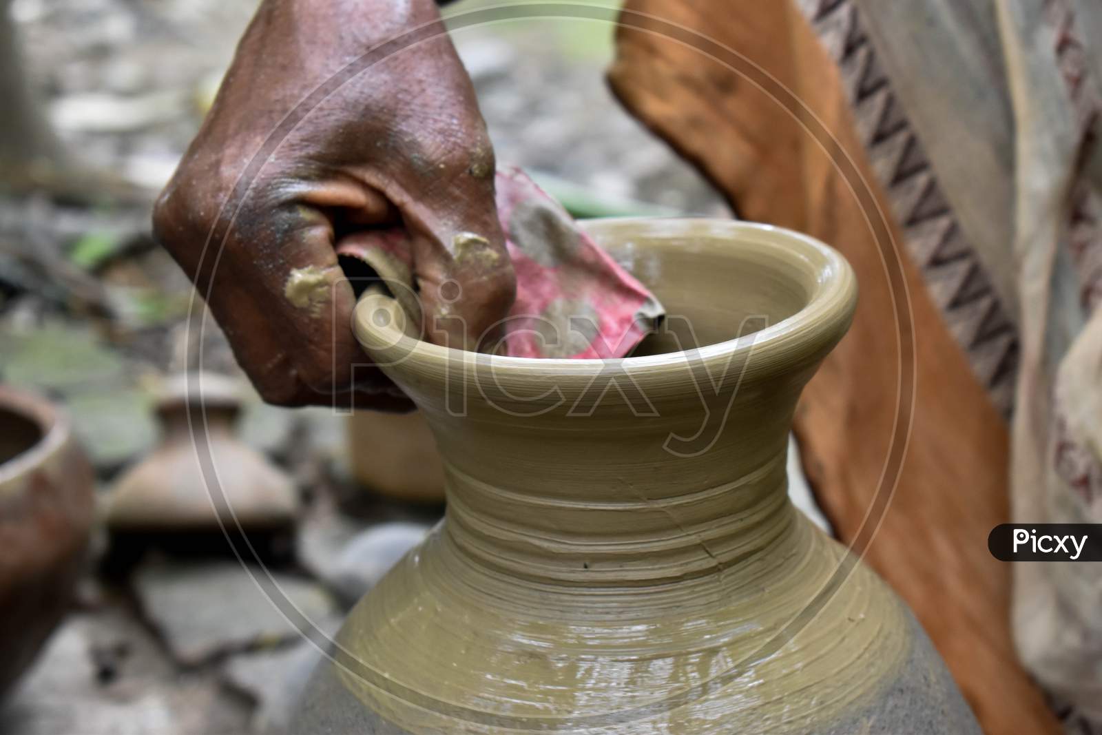 A potter is making beautiful clay pots using his potter's wheel, it is his job. If you want to make a clay pot, first you have to get good soil, then you can make a clay pot with the help of hands and wheels.