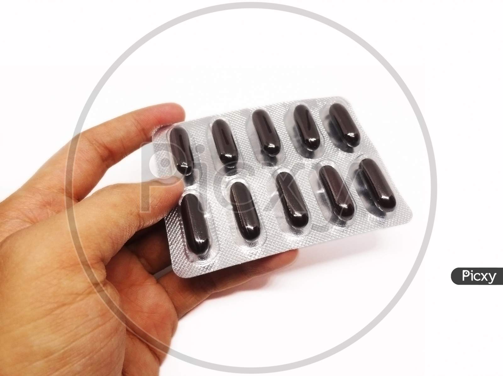 Black color multivitamin capsule pills holding in hand on white background