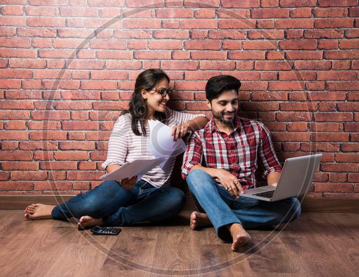 Indian Asian Young Couple Accounting, Calculating Bills, Planning Budget For Home Loan Using Laptop